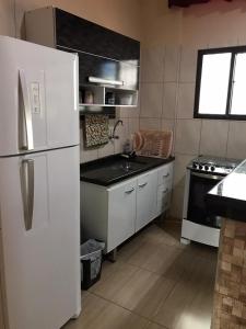 a kitchen with a white refrigerator and a sink at Apartamento no Centro de Mongaguá in Mongaguá