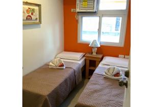 two beds in a room with a window at Stone House Hotel Pasay in Manila