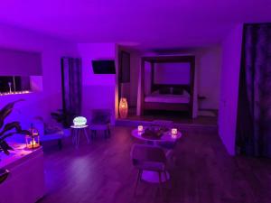 a purple room with a living room with a bed at L escapade amoureuse in Bournezeau