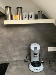 uma máquina de café branca sentada debaixo de uma prateleira em zentrales Dachgeschossapartment in Leichligen em Leichlingen