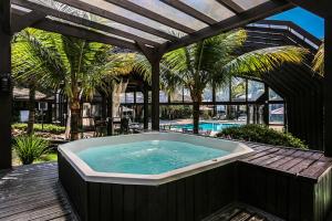 a hot tub on a deck next to a pool at Estaleiro Guest House in Balneário Camboriú