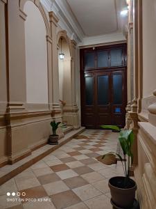 a hallway with a door and a tiled floor with plants at Konzul in Osijek
