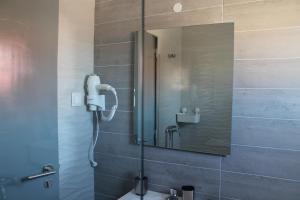 a shower with a mirror and a sink in a bathroom at Hospedaria Da Barragem in Montargil