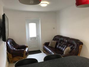 a living room with two leather couches and a window at Victoria House in Poole