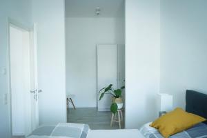- une chambre avec des murs blancs et un lit avec un oreiller jaune dans l'établissement Prime Park Deluxe Apartment Aschaffenburg, à Aschaffenbourg