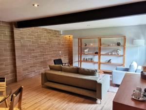 a living room with a couch and a brick wall at Hotel Boutique Unico Avandaro in Valle de Bravo