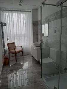 a bathroom with a shower and a sink and a chair at Žlutý apartmán A6 v Chomutově in Chomutov