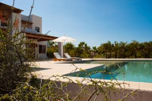 a pool with two chairs and an umbrella next to a house at Tribu Todos Santos in Todos Santos
