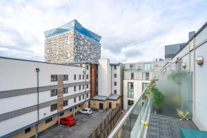 AJY Birmingham City Centre Viva Apartment في برمنغهام: اطلالة من الشرفة على مبنى مع موقف للسيارة