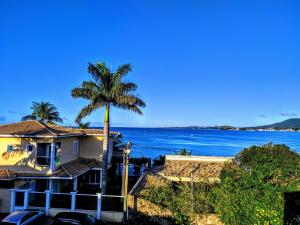 a house with a palm tree in front of the ocean at Cobertura da Lagoa, andar inteiro in São Pedro da Aldeia