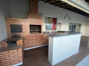 an outdoor kitchen with a brick fireplace in a house at Cobertura da Lagoa, andar inteiro in São Pedro da Aldeia