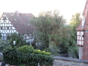 an old black and white building with trees and bushes at Turmstüble im Torhaus von 1545 in Burgbernheim