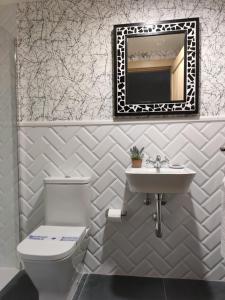 a bathroom with a toilet and a sink and a mirror at La Onda in Ramales de la Victoria