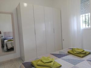 Habitación blanca con mesa y toallas verdes. en Chalet Costa de la Luz - La Barrosa, en Chiclana de la Frontera