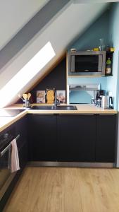a kitchen with a sink and a microwave at La Nacelle, classée 3 étoiles, vue dégagée port et mer in Le Tréport