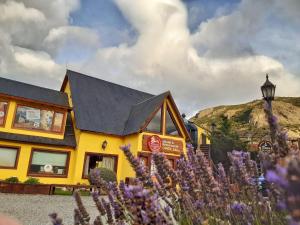 a restaurant with purple flowers in front of it at Rancho Grande Hostel in El Chalten