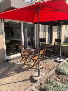 une table et des chaises sous un parasol rouge sur une terrasse dans l'établissement Strandwandeling 2 slaapkamers, à Coxyde 9 autres photos
