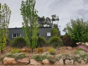 a house in a garden with trees and plants at Equestrian Farm Stay in One Tree Hill