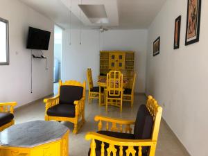 a dining room with yellow chairs and a table at Palmarito Beach Apartamentos in Carretal