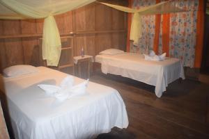 una camera con due letti con lenzuola e archi bianchi di Lodge Jungle Wolf Expeditions a Yucuruche