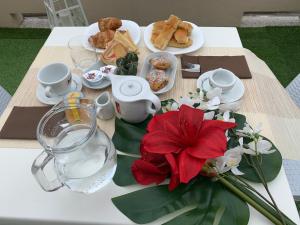 einen Tisch mit einem Teller Essen und einer roten Blume darauf. in der Unterkunft Domus Victoria in Genua