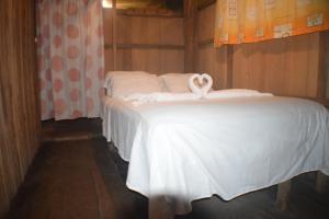 a bed with white sheets and a ribbon on it at Lodge Jungle Wolf Expeditions in Yucuruche