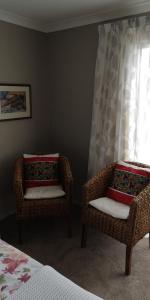 two wicker chairs sitting in a bedroom with a window at Grampians B&B in Nelson