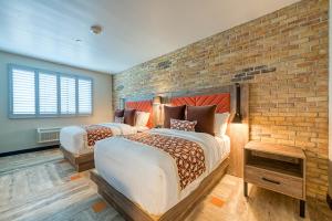 two beds in a room with a brick wall at Hotel Lexen Newhall & Santa Clarita - Near Six Flags Magic Mountain in Santa Clarita