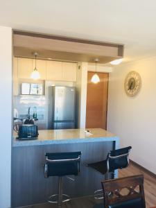 a kitchen with a counter with chairs and a refrigerator at Departamento Freire 1905 in Concepción