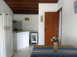una cocina con nevera y un jarrón con flores. en By Búzios Loft, en Búzios 34 fotos más