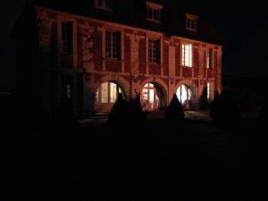um edifício à noite com as luzes acesas em L’orangerie chambres d’hôtes em Motteville