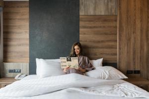a woman sitting on a bed reading a book at Acqua Hotel in Pattaya