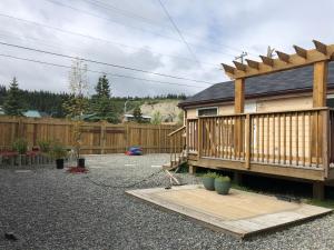 a backyard with a wooden deck and a fence at Midnight Sun Vacation Home in Whitehorse