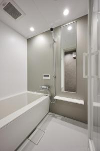 ein weißes Badezimmer mit Dusche und Spiegel in der Unterkunft Colors Hakata in Fukuoka + 22 Fotos