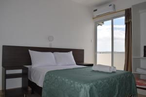 ein Schlafzimmer mit einem Bett mit einer grünen Decke und einem Fenster in der Unterkunft Mare S&M Casa Hostal in Manta