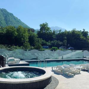 a pool with a hot tub and chairs and a fence at Apartmani Lux Novalić in Konjic