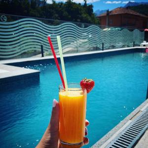 a hand holding a drink with a strawberry in it at Apartmani Lux Novalić in Konjic
