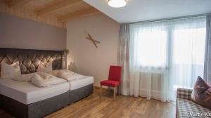 ein Schlafzimmer mit einem Bett und einem roten Stuhl in der Unterkunft Apart Hotel Arno in Sölden