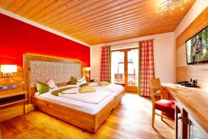 a bedroom with a large bed and a red wall at Hotel am Wiesenhang - Garni in Bad Kohlgrub