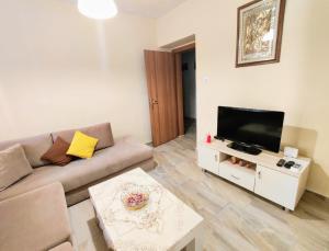 sala de estar con sofá y TV de pantalla plana en Tirana City Center Apartment, en Tirana