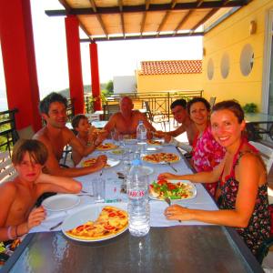 a group of people sitting at a table eating pizza at Saint Catherine Hotel in Pythagoreio