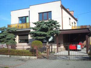 une maison blanche avec une clôture et un arbre dans l'établissement Kwatery Pokoje Mira, à Poznań