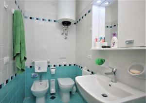 La salle de bains bleue et blanche est pourvue d'un lavabo et de toilettes. dans l'établissement Villa Ralph, à Lignano Sabbiadoro