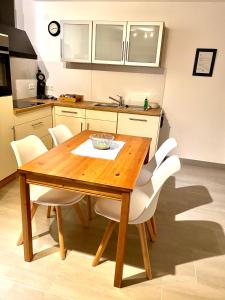 a kitchen with a wooden table and white chairs at Gästehaus am Pfarrgarten in Mettlach