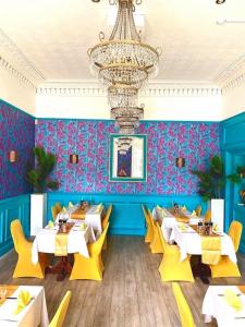 um restaurante com mesas e cadeiras amarelas e um lustre em The Elms Hotel em East Retford