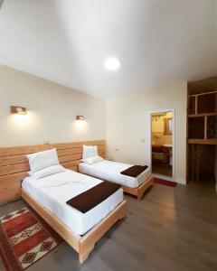 two beds in a large room with a mirror at At Pikotiko's - Korca City Rooms for Rent in Korçë