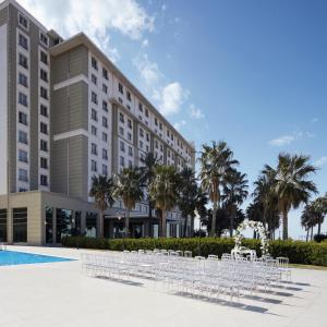 een hotel met tafels en stoelen voor een gebouw bij Anemon Iskenderun Hotel in İskenderun