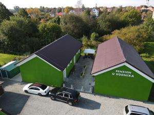 two green buildings with cars parked in a parking lot at Penzion u Vodníka in Třeboň