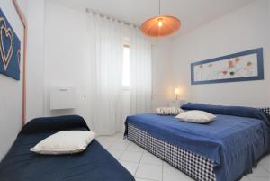 リニャーノ・サッビアドーロにあるAppartamenti Alidecoのベッドルーム1室(青いシーツが備わるベッド2台付)