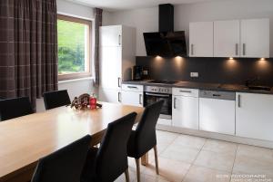 a kitchen with a wooden table and black chairs at Appartments Am Bach in Gerlos